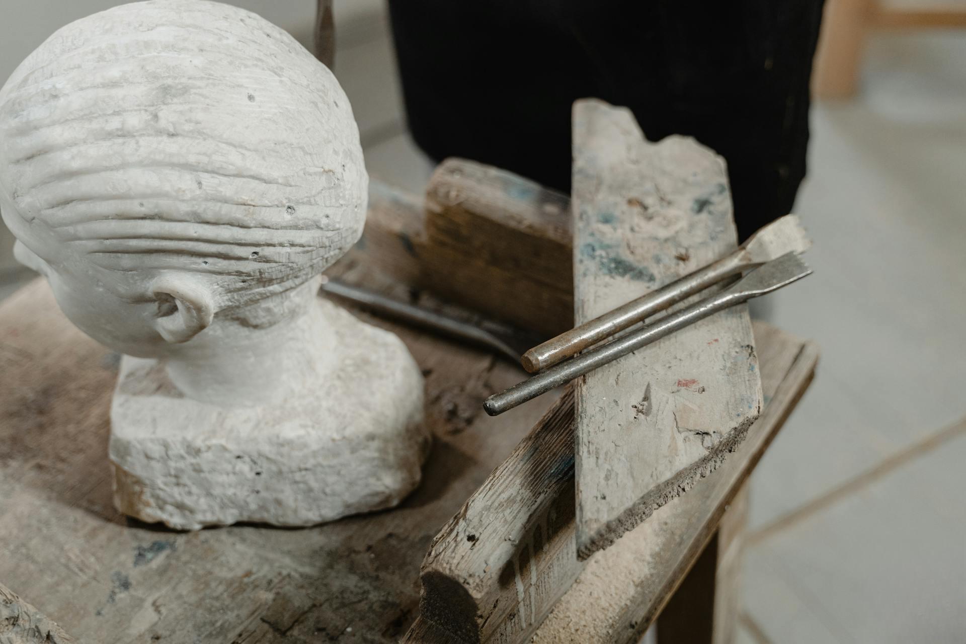 Testa di scultura in marmo su tavolo con strumenti da atelier